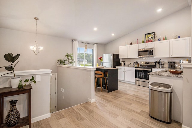 7762 Sierra Dr, Belding, MI 48809 - kitchen featuring appliances with stainless steel finishes, vaulted ceiling, a kitchen breakfast bar, a sink, and white cabinets
