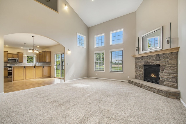 14275 Sunset Ridge Ct, Niles, MI 49120 - unfurnished living room with high vaulted ceiling, light carpet, baseboards, a fireplace, and arched walkways