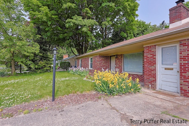 3904 Canterbury Ave, Kalamazoo, MI 49006 - view of property exterior featuring brick siding, a chimney, and a lawn