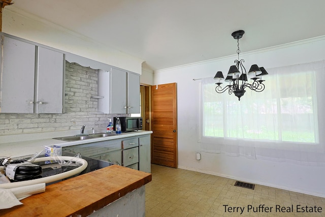 3904 Canterbury Ave, Kalamazoo, MI 49006 - kitchen featuring a sink, black microwave, a chandelier, hanging light fixtures, and baseboards