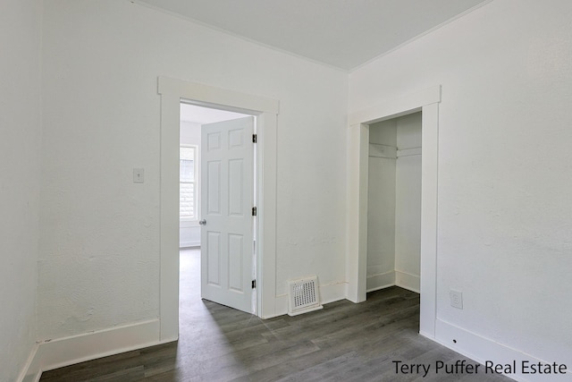 unfurnished bedroom with dark wood finished floors, baseboards, and a closet