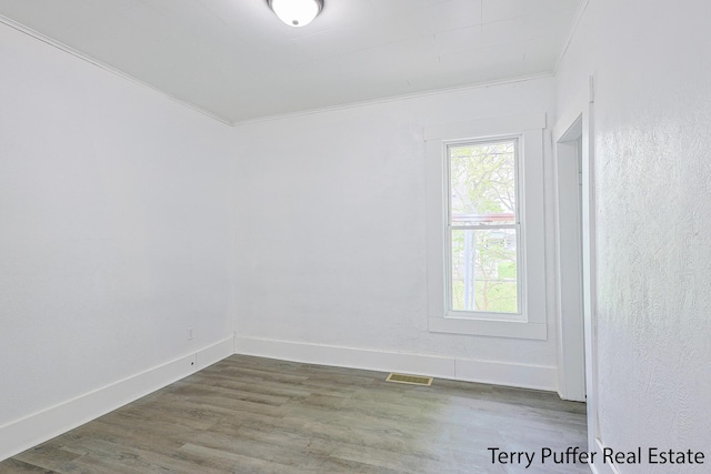 spare room featuring baseboards, wood finished floors, and ornamental molding