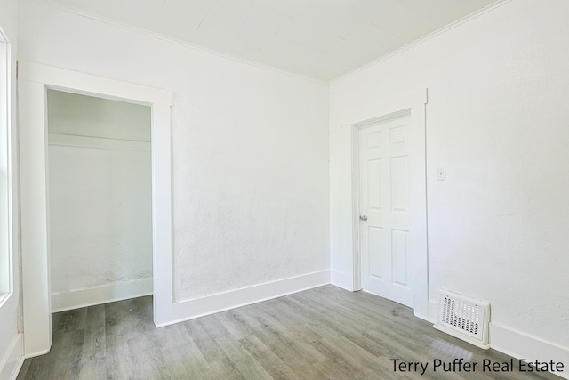 unfurnished bedroom featuring ornamental molding, wood finished floors, and baseboards