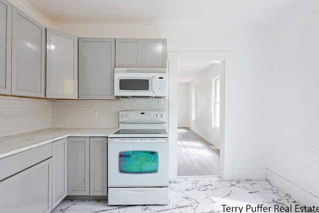 kitchen with gray cabinets, white appliances, light marble finish floors, ornamental molding, and decorative backsplash