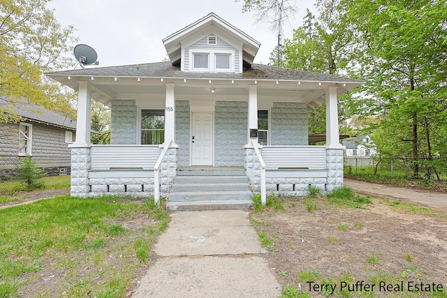 view of front of house with covered porch, fence, and roof with shingles