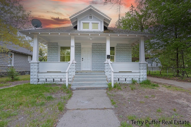 view of front of home featuring a porch and fence