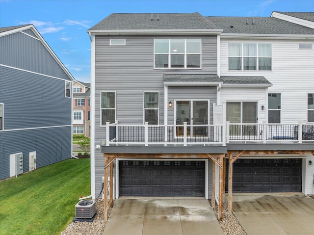back of property with central AC unit, a garage, concrete driveway, and a lawn
