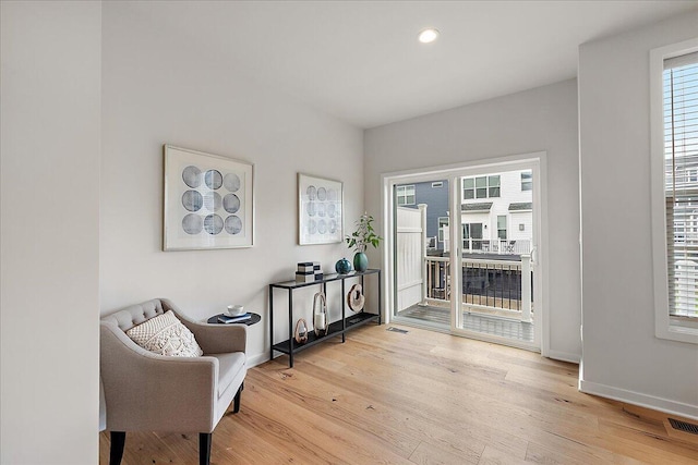 living area featuring light wood-style flooring, baseboards, and recessed lighting