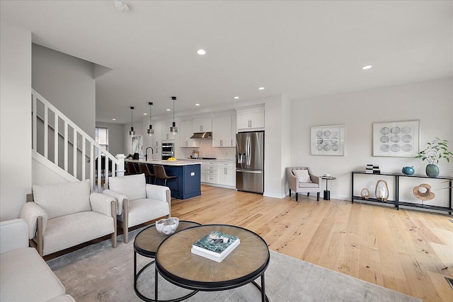 living room with light wood-style flooring, stairway, and recessed lighting