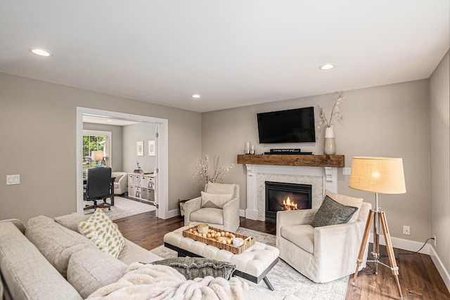living area with recessed lighting, wood finished floors, baseboards, and a premium fireplace