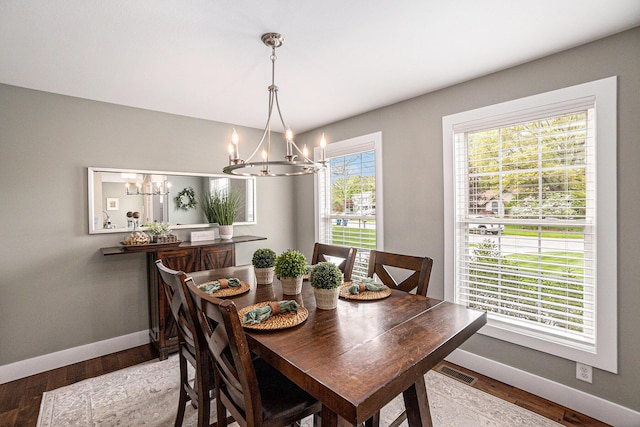 dining space featuring a chandelier, baseboards, and wood finished floors