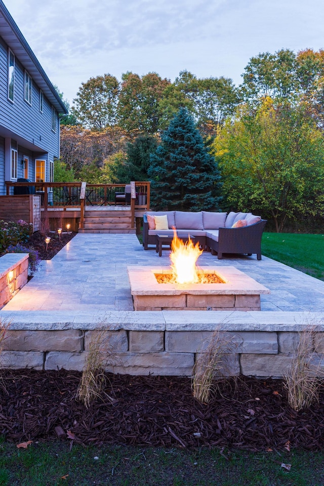 wooden terrace featuring an outdoor living space with a fire pit and a patio