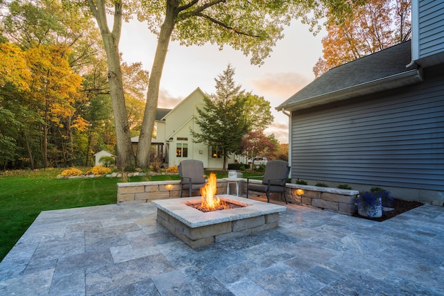 patio terrace at dusk with a fire pit and a yard