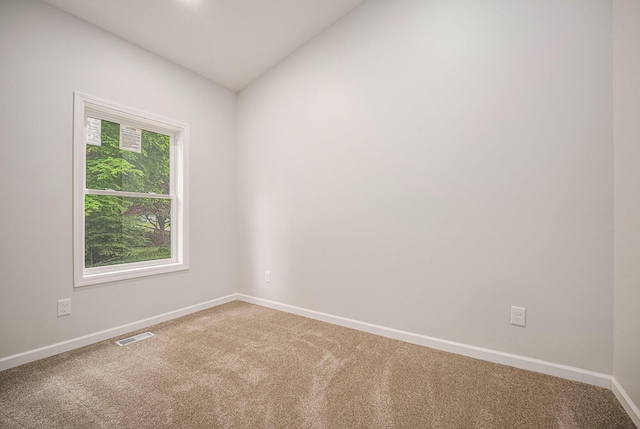 empty room with carpet, baseboards, and lofted ceiling