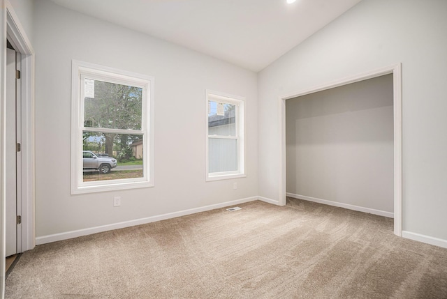 unfurnished bedroom featuring carpet flooring, vaulted ceiling, multiple windows, and baseboards