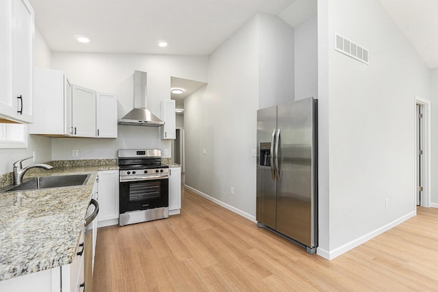 408 W Exchange St, Gobles, MI 49055 - kitchen featuring appliances with stainless steel finishes, wall chimney exhaust hood, a sink, light wood finished floors, and high vaulted ceiling