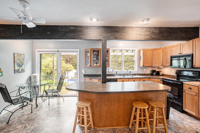 kitchen featuring black appliances, a kitchen bar, a kitchen island, dark countertops, and a textured ceiling