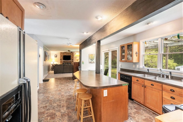 kitchen with black dishwasher, stone finish flooring, open floor plan, a kitchen breakfast bar, and glass insert cabinets