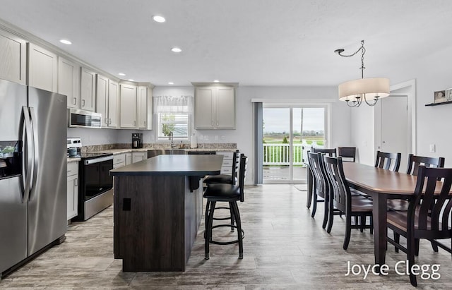 4755 Boulder Dr, Holland, MI 49423 - kitchen featuring appliances with stainless steel finishes, a center island, a kitchen bar, light wood-type flooring, and recessed lighting