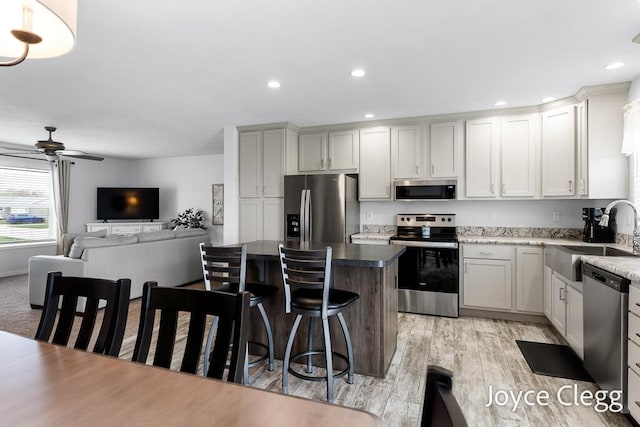 4755 Boulder Dr, Holland, MI 49423 - kitchen featuring appliances with stainless steel finishes, a sink, a ceiling fan, a kitchen island, and a kitchen breakfast bar