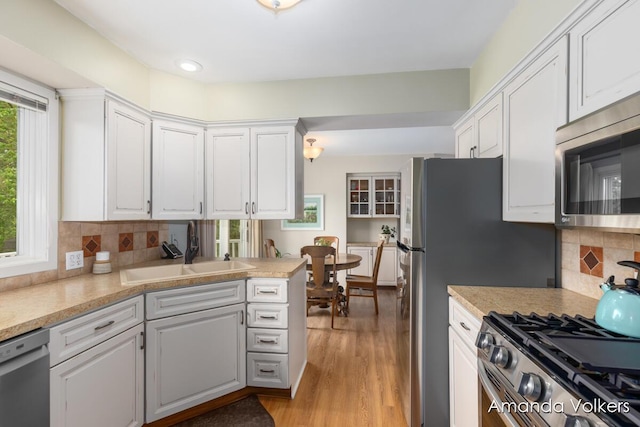 kitchen featuring appliances with stainless steel finishes, a sink, white cabinetry, light wood-style flooring, and recessed lighting