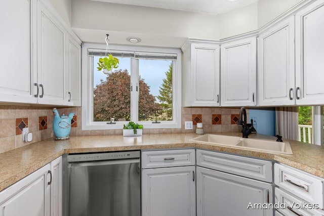 kitchen featuring stainless steel dishwasher, a sink, white cabinets, and light countertops