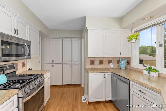 kitchen with appliances with stainless steel finishes, white cabinetry, and decorative backsplash