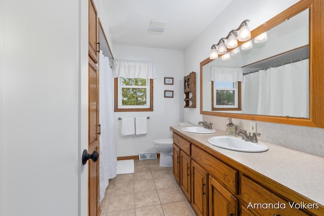 bathroom with double vanity, toilet, tile patterned floors, and baseboards