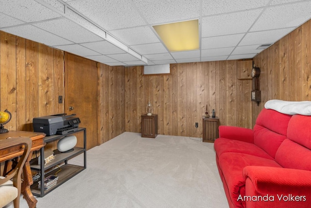 carpeted office featuring wooden walls and a paneled ceiling