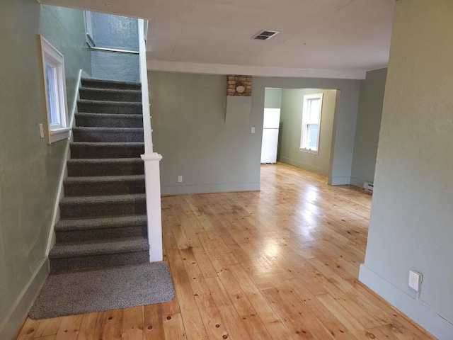 stairs featuring wood-type flooring, baseboards, and baseboard heating