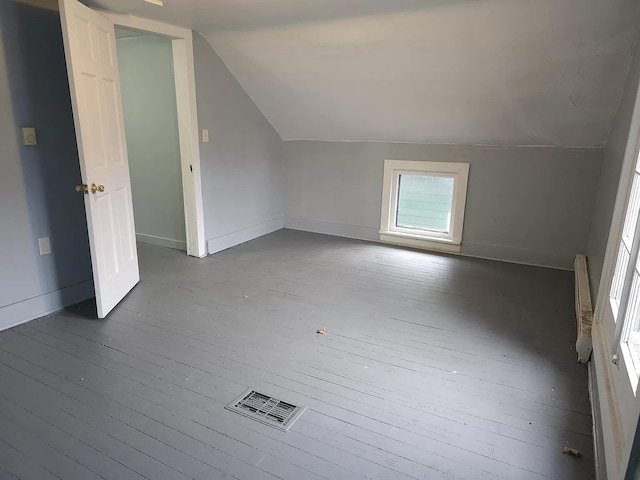 bonus room with vaulted ceiling, dark wood-style floors, and baseboards