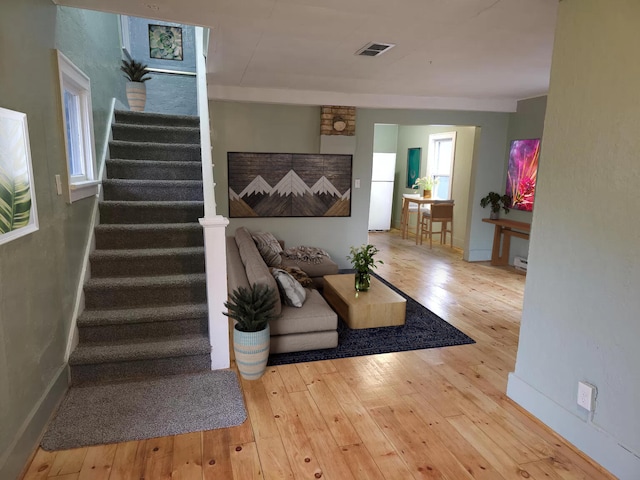 living area with stairway, wood-type flooring, and baseboards