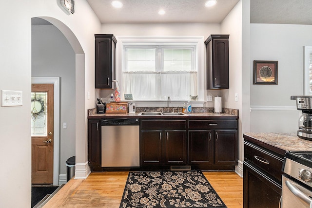 705.5 E Ludington Ave, Ludington, MI 49431 - kitchen featuring dishwasher, a sink, arched walkways, light wood-style floors, and plenty of natural light