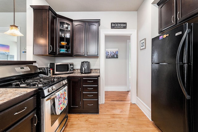 705.5 E Ludington Ave, Ludington, MI 49431 - kitchen featuring appliances with stainless steel finishes, dark brown cabinetry, light wood-style flooring, and glass insert cabinets