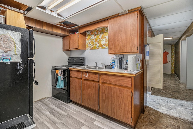 kitchen with black appliances, brown cabinetry, a sink, light countertops, and light wood-style floors