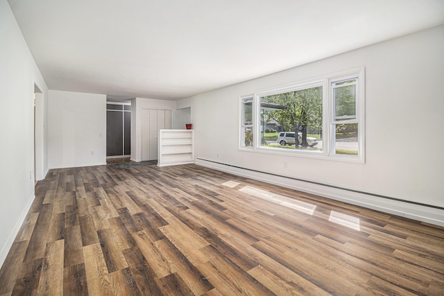 unfurnished bedroom with wood finished floors, a baseboard radiator, and baseboards