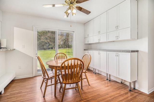 dining room with ceiling fan, light wood-style floors, and baseboards