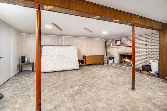 finished basement featuring a fireplace, brick wall, and wooden walls