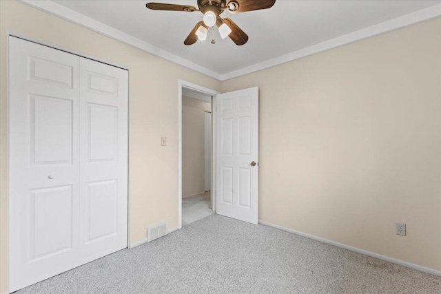 unfurnished bedroom featuring carpet flooring, ornamental molding, baseboards, a closet, and a ceiling fan