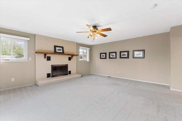 unfurnished living room featuring a ceiling fan, carpet flooring, baseboards, and a brick fireplace