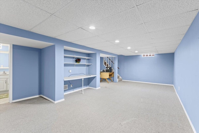 finished below grade area with carpet flooring, baseboards, stairs, recessed lighting, and a drop ceiling