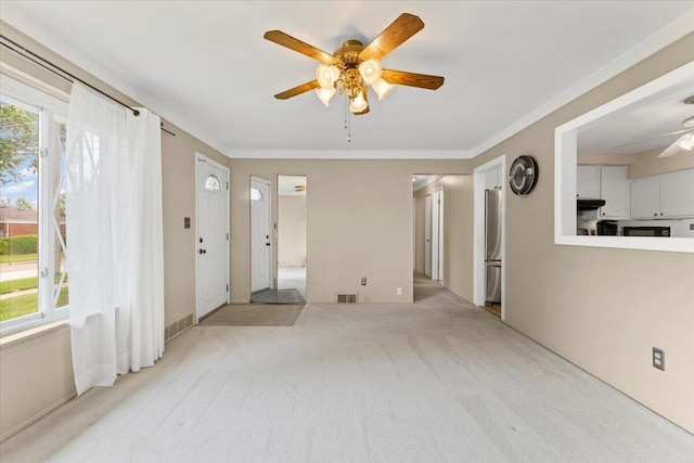 carpeted spare room with a ceiling fan and crown molding