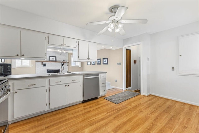 kitchen featuring stainless steel dishwasher, a sink, black microwave, light wood-style flooring, and baseboards