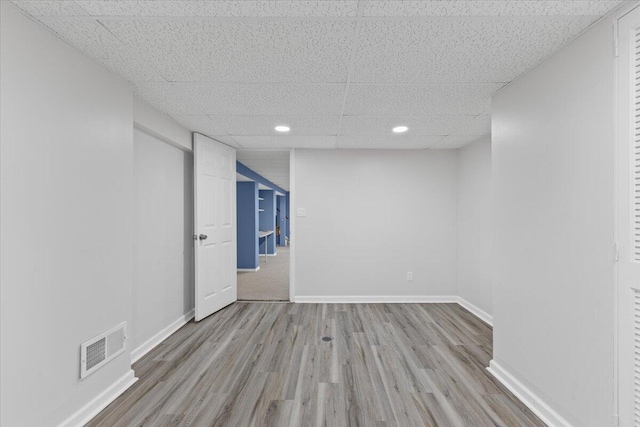 unfurnished room with wood finished floors, baseboards, a drop ceiling, and recessed lighting