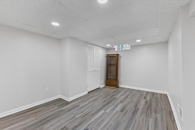 finished basement featuring wood finished floors, a paneled ceiling, baseboards, and recessed lighting