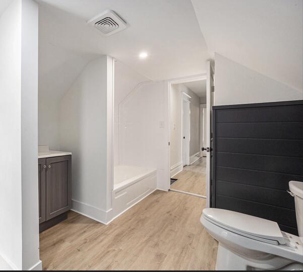 2145 Horton Ave SE, Grand Rapids, MI 49507 - bathroom featuring toilet, wood finished floors, vaulted ceiling, and baseboards