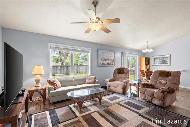 living room featuring wood finished floors, a chandelier, ceiling fan, lofted ceiling, and a textured ceiling