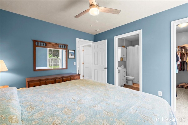 bedroom with a spacious closet, a closet, connected bathroom, and a ceiling fan