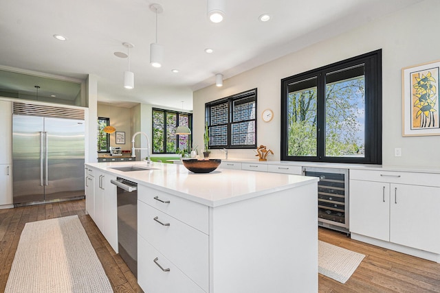 1950 Robinson Rd SE, East Grand Rapids, MI 49506 - kitchen featuring stainless steel appliances, a sink, beverage cooler, a center island with sink, and light wood-style flooring