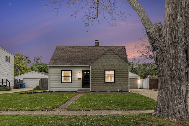 view of front facade featuring a garage, a chimney, a shingled roof, and an outbuilding
